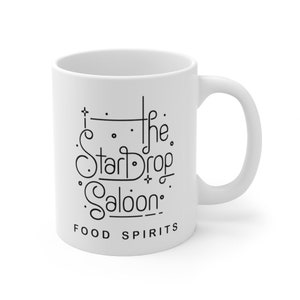 May include: White ceramic mug with black text that reads "The Star Drop Saloon" and "Food Spirits".