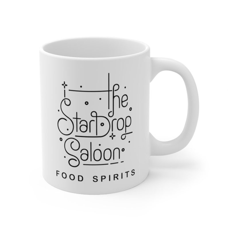 May include: White ceramic mug with black text that reads "The Star Drop Saloon" and "Food Spirits".