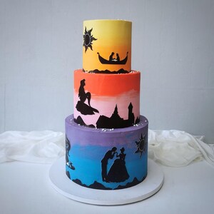 May include: A three-tiered cake with a gradient of colors, featuring black silhouette designs. The top tier is yellow, the middle is orange, and the bottom is purple and blue. Silhouettes depict a boat, mermaid, and couple.