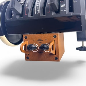 May include: A black and gray flight simulator throttle quadrant with multiple levers and dials. A brown box with the text "FUEL CONTROL RUN" is attached below. The device is designed for flight simulation.