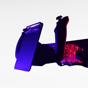 May include: A black and red gaming chair with a blue and purple light. The chair has a headrest and a lumbar support.