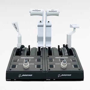 May include: A gray and black Thrustmaster flight simulator control panel with two throttle levers, two white levers labeled "DISENGAGE", and a white lever labeled "SPO BRK". The panel has a black label that reads "THRUSTMASTER" and a gray label that reads "BOEING".