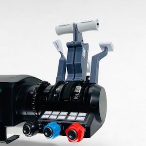 Puede incluir: Un panel de control de simulador de vuelo negro con múltiples botones, perillas e interruptores. El panel también presenta dos palancas de acelerador con manijas blancas y el texto "DISENGAGE" impreso en ellas. El panel tiene un botón azul y rojo en el lado derecho.