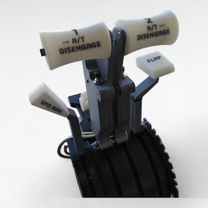 Könnte beinhalten: Nahaufnahme eines schwarzen Flugzeug-Bedienfelds mit weißen Hebeln und Knöpfen. Die Hebel sind mit "1 A/T DISENGAGE", "2 A/T DISENGAGE", "FLAP" und "SPD BRK" beschriftet.