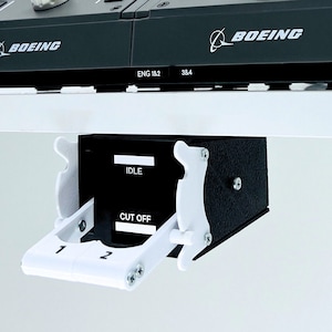 May include: A black box with white levers and the words "IDLE" and "CUT OFF" on it. The box is mounted to a white surface.