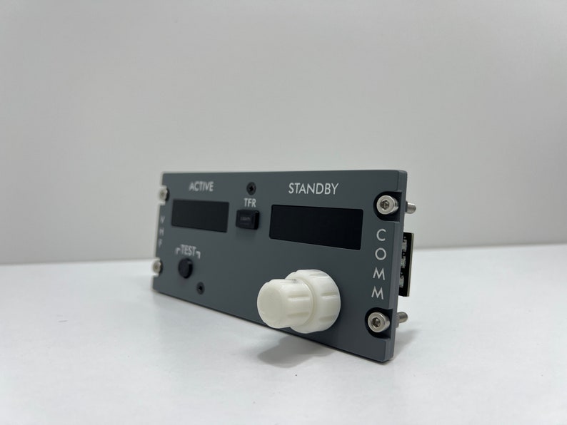 May include: Gray aircraft communication panel with a white knob, labeled "ACTIVE", "STANDBY", "TFR", "TEST", and "COMM".