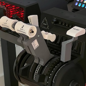 May include: Close-up of a black aircraft control panel with white levers and buttons. The levers are labeled "A/T - DISENGAGE" and "FLAP". The buttons are labeled "SPD B", "GEAR", "AUTO PILOT", and "FLAPS".