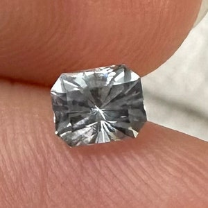 May include: A clear, faceted, rectangular gemstone with a slight gray hue.