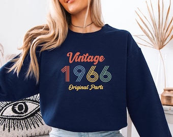May include: A navy blue crewneck sweatshirt featuring the text Vintage 1966 Original Parts in a retro-style font. The word Vintage is in orange, the number 1966 is in multi-coloured striped lines, and the words Original Parts are in yellow.