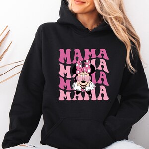 May include: Black hooded sweatshirt with the word "MAMA" in pink, stacked four times, with a Minnie Mouse graphic in the center. Minnie Mouse is wearing a pink bow with white polka dots.