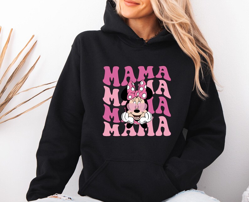May include: Black hooded sweatshirt with the word "MAMA" in pink, stacked four times, with a Minnie Mouse graphic in the center. Minnie Mouse is wearing a pink bow with white polka dots.
