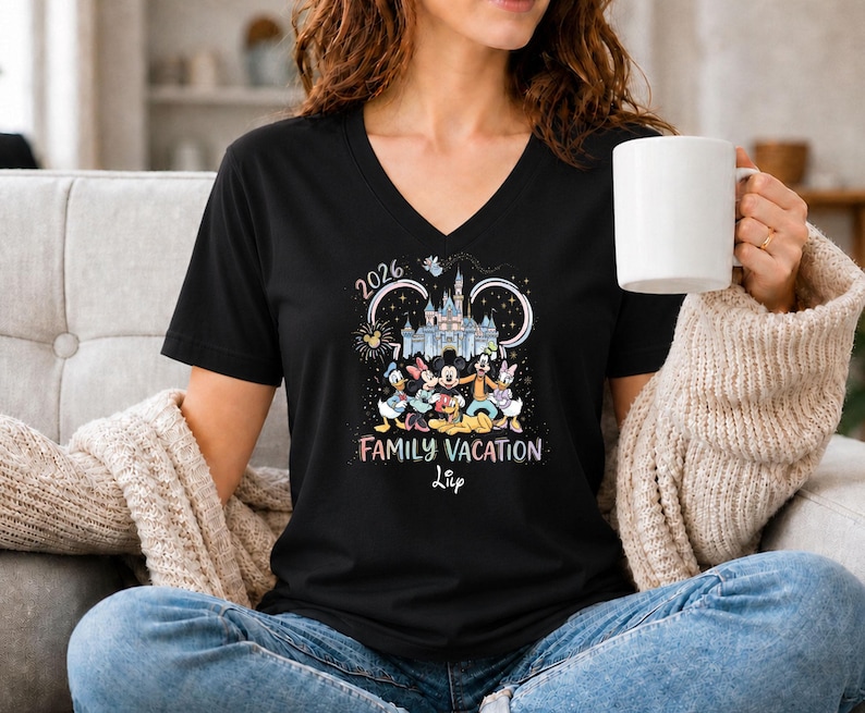 May include: Black V-neck t-shirt featuring a colorful graphic of Disney characters in front of a castle, with the text "2026 Family Vacation". The shirt is a comfortable, casual style.