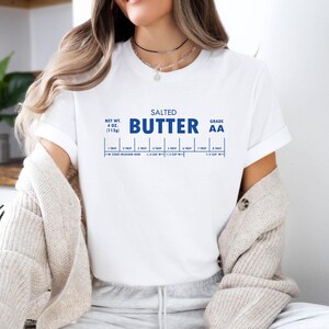 May include: White t-shirt with a blue graphic that reads "SALTED BUTTER GRADE AA" and includes a measurement chart for tablespoons and cups.