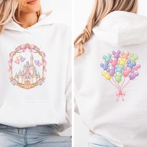 May include: White hooded sweatshirt featuring a pastel castle design framed by a pink ribbon and floral accents on the front. The back displays a cluster of colorful Mickey Mouse-shaped balloons tied with a pink bow. A cozy, casual top.