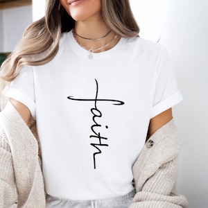 Peut inclure: T-shirt blanc avec une croix noire et le mot "foi" &eacute;crit verticalement au centre de la croix.