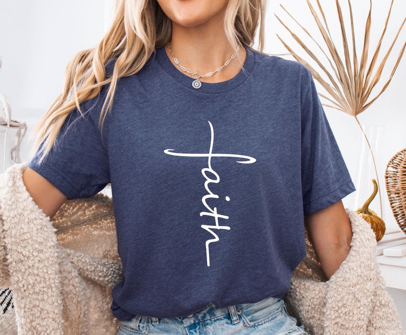 Peut inclure: Un t-shirt bleu marine avec une croix blanche et le mot "foi" &eacute;crit verticalement au centre de la croix.