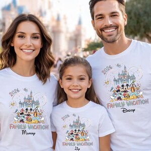 May include: White t-shirts with a colorful graphic featuring Disney characters, a castle, and the text "2026 Family Vacation." The shirts are worn by a family, with the text "Mummy," "Daddy," and "Lia" below the graphic.