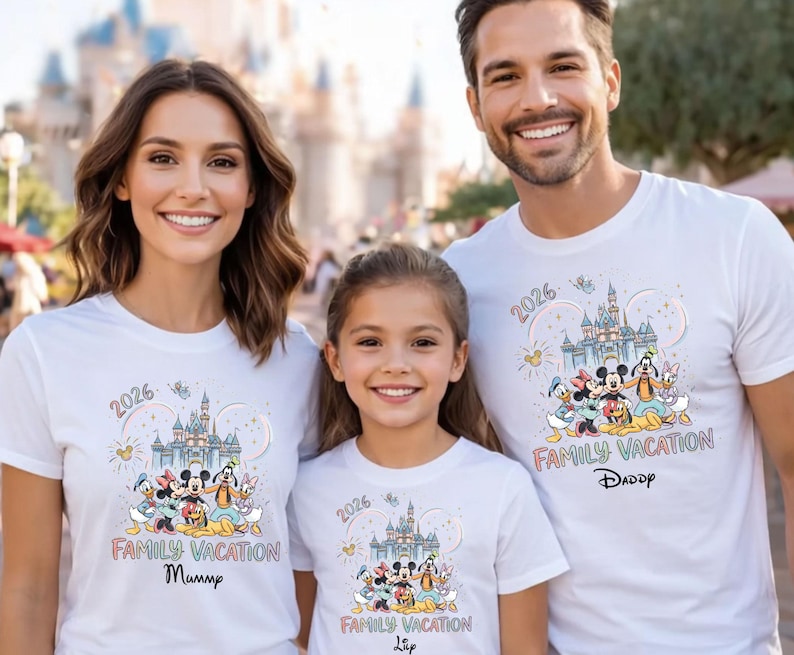 May include: White t-shirts with a colorful graphic featuring Disney characters, a castle, and the text "2026 Family Vacation." The shirts are worn by a family, with the text "Mummy," "Daddy," and "Lia" below the graphic.