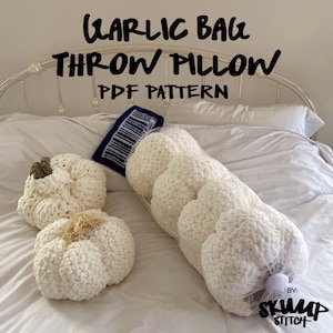 Puede incluir: Cojines decorativos con forma de ajo, de ganchillo, de color crema. Un cojín está en una bolsa de red, y dos están separados. El texto "GARLIC BAG THROW PILLOW PDF PATTERN" está en la parte superior de la imagen.
