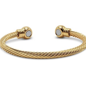 May include: A gold-toned magnetic bracelet with a twisted cable design. The bracelet has two round magnetic clasps.
