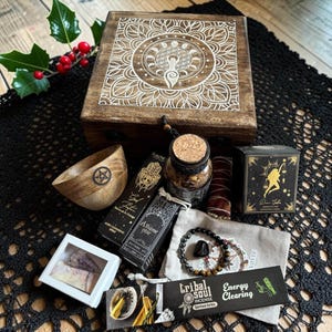 Può includere: Una scatola di legno con un design mandala bianco, una ciotola di legno con un pentacolo, un barattolo di vetro con tappo in sughero, una scatola nera 'Dream Goddess', una scatola nera 'Tribal Soul', un braccialetto di perline, una piccola scatola bianca e olio profumato.
