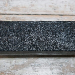 May include: A black rectangular box with an intricate embossed floral pattern.