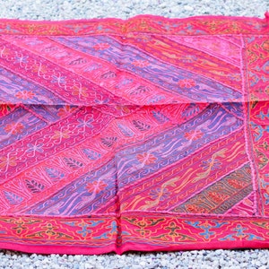 Puede incluir: Una manta de patchwork rosa y morada con un patrón floral y un borde decorativo. La manta está hecha de algodón y es perfecta para agregar un toque de color y estilo a cualquier habitación.