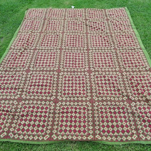 May include: A large red and green patterned picnic blanket with a geometric design. The blanket is made of a woven fabric and has a fringed edge.