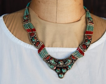 May include: A multi-strand necklace with turquoise and red coral beads. The necklace has a large, ornate pendant with turquoise and silver accents.