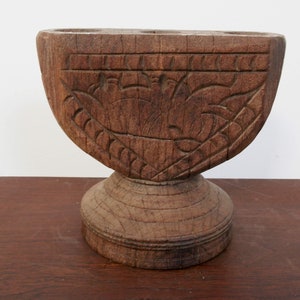 Può includere: Un candelabro in legno intagliato con una base larga e quattro portacandele. Il candelabro è decorato con un motivo floreale.