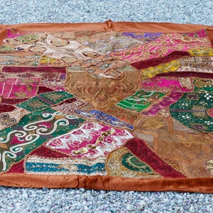 Puede incluir: Un tapiz de patchwork colorido con un borde marrón. El tapiz está hecho de varias telas y está decorado con cuentas, lentejuelas y bordados.