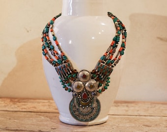 May include: A multi-strand necklace with turquoise, coral, and amber beads. The necklace has a large silver pendant with intricate designs and turquoise stones.
