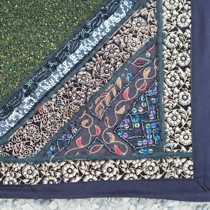 May include: A multi-colored patchwork fabric with a black border. The fabric is decorated with sequins, embroidery, and floral patterns.