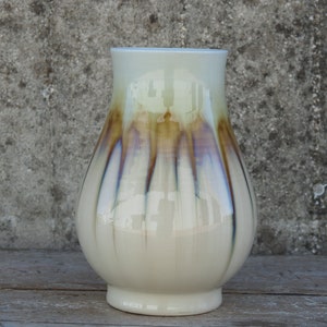 Peut inclure: Un vase en céramique blanche de forme bulbeuse avec un glaçage brun et bleu. Le glaçage a un effet strié, créant un aspect unique et artistique.