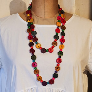 May include: A multi-coloured necklace made of wooden buttons. The necklace is made of two strands of buttons, with each strand featuring a variety of colours, including red, yellow, green, blue, and brown. The buttons are all round and have a slightly raised centre.