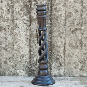 Peut inclure: Un chandelier en bois noir avec un design torsadé. Le chandelier a une base large et une tige haute et mince.