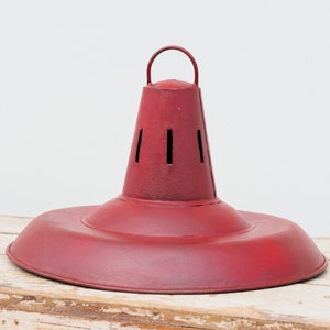 Può includere: Paralume in metallo rosso con base rotonda e piatta e parte superiore conica con dettagli ritagliati. Il paralume ha una maniglia nella parte superiore.