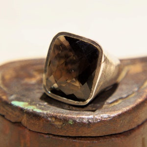Può includere: Un anello d'argento con una grande pietra rettangolare di colore marrone scuro.