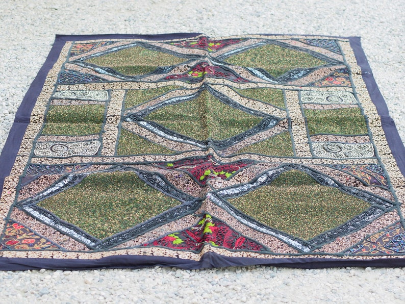 May include: A patchwork quilt with a diamond pattern in shades of green, black, and red. The quilt is decorated with sequins and embroidery.