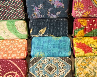 Puede incluir: Una pila de diez carteras de tela coloridas con varios patrones, incluyendo diseños florales, geométricos y paisley. Las carteras están hechas de tela acolchada y tienen una estética vintage.