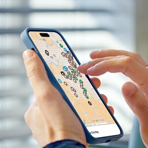 Puede incluir: Un smartphone con una funda azul muestra un mapa con numerosos marcadores de ubicaci&oacute;n. La pantalla muestra un mapa detallado de la ciudad con varios iconos de colores, que sugieren puntos de inter&eacute;s o ubicaciones. Una mano toca la pantalla.