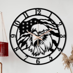 Könnte beinhalten: Schwarze Wanduhr mit Adler- und amerikanischer Flaggen-Design. Die Uhr hat römische Ziffern und einen Holzzeiger.