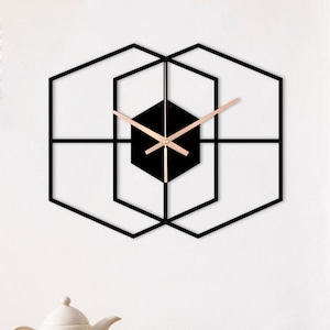 May include: A black geometric wall clock with gold hands. The clock is made of metal and has a modern design.