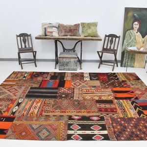 Könnte beinhalten: Ein bunter Patchwork-Teppich mit verschiedenen geometrischen Mustern in Rot-, Orange-, Braun-, Schwarz- und Blautönen. Der Teppich ist aus gewebtem Stoff gefertigt und hat einen abgenutzten, Vintage-Look.