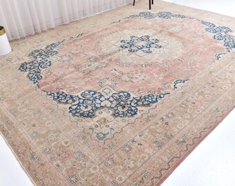 May include: Large, rectangular area rug with a central medallion and ornate border. The rug features a faded, vintage aesthetic with a color palette of blush pink, beige, and navy blue. The design includes floral and geometric patterns.