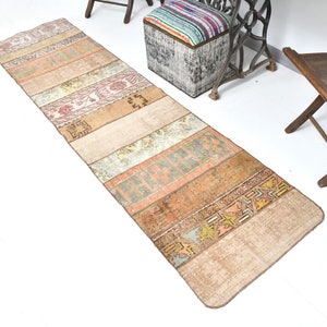 May include: A long, rectangular rug with a patchwork design. The rug is made of different colored fabrics, including beige, brown, orange, and red. The rug has a vintage look and is perfect for adding a touch of bohemian style to any room.