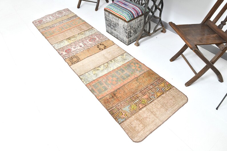 May include: A long, rectangular rug with a patchwork design. The rug is made of different colored fabrics, including beige, brown, orange, and red. The rug has a vintage look and is perfect for adding a touch of bohemian style to any room.