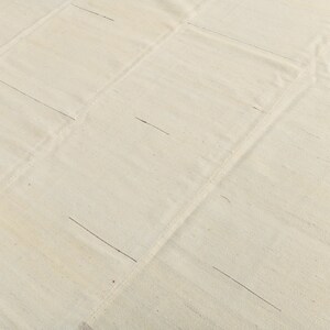 May include: A plain white fabric rug with a grid pattern of lines sewn into the fabric.