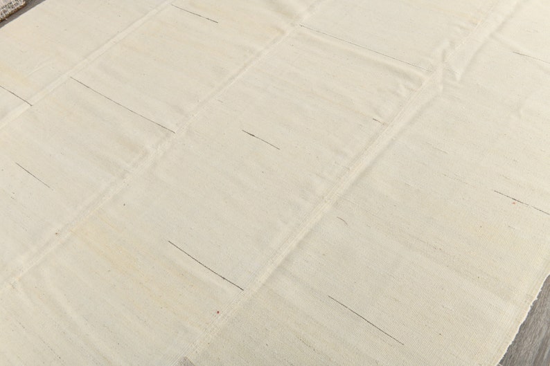 May include: A plain white fabric rug with a grid pattern of lines sewn into the fabric.