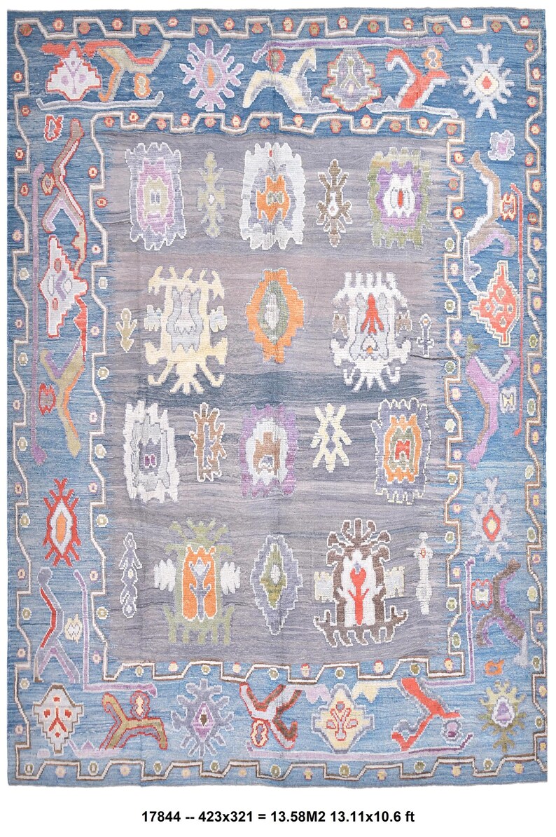 May include: A large, rectangular rug with a blue border and a central field of grey and blue. The rug features a repeating pattern of stylized floral and geometric motifs in shades of orange, purple, and white. The rug measures 4.00 x 3.23 metres.